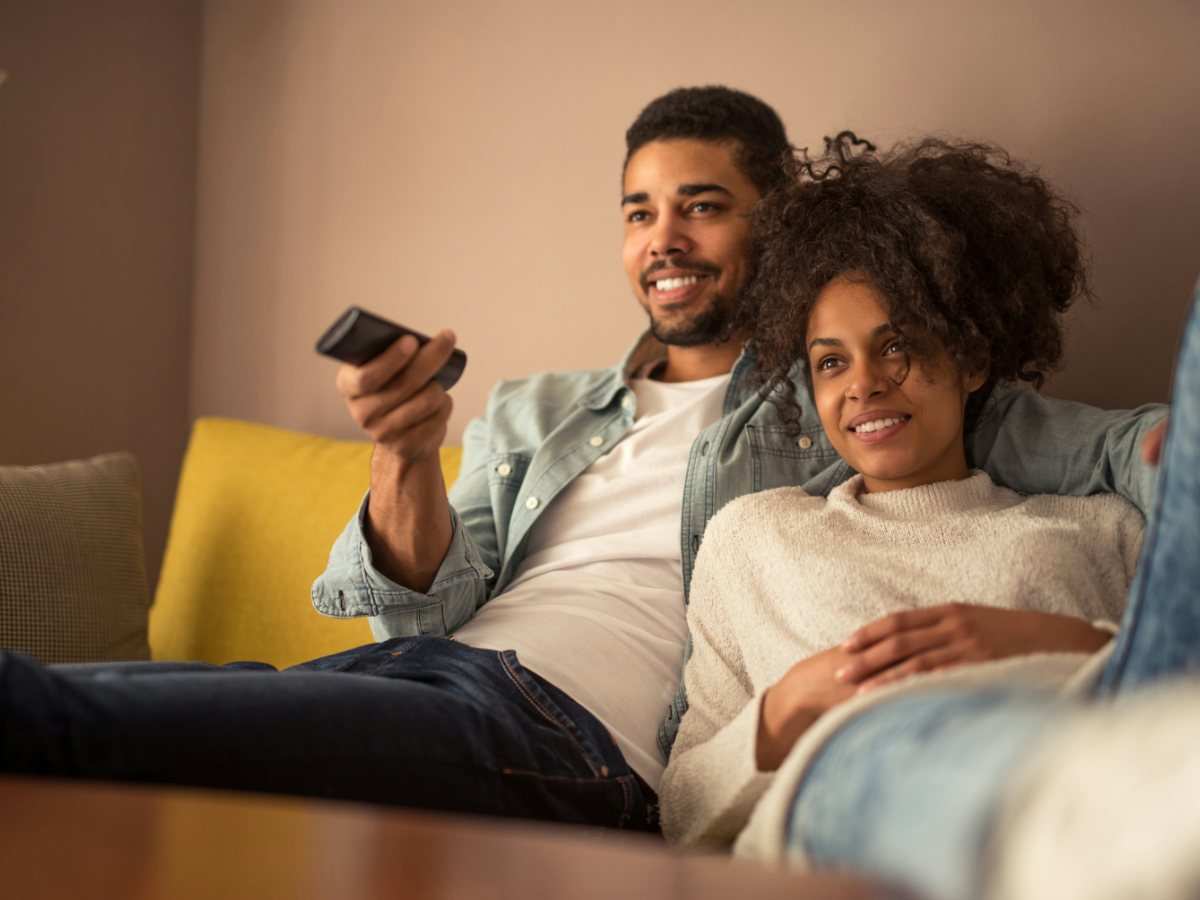 A couple choosing what to watch with a remote control
